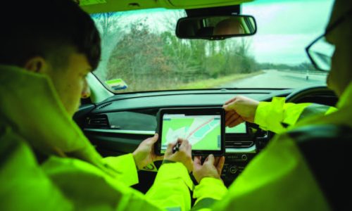 2 people in Hi-viz in a car working on a tablet screen